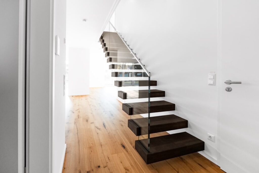Moderne Kragarmtreppe mit dunklen Stufen und Glasgeländer