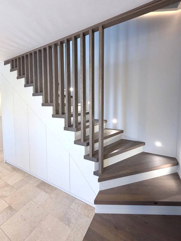 aufgesattelte Holztreppe mit Einbauschrank und raumhohem Lamellengeländer